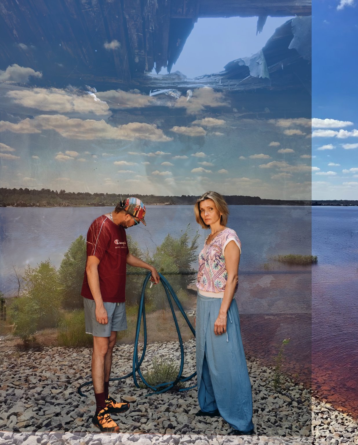 Zwei Personen, eine m&auml;nnlich und eine weiblich gelesene stehen an einem Kiesstrand, im Hintergrund der See und Himmel. Die Frau blickt kritisch in die Kamera, der Mann hat sein Gesicht abgewendet und blickt auf einen Wasserschlauch in seiner Hand. &Uuml;berlagert wird das Bild vom Bild einer Hausruine. | © Leonie Ohlow